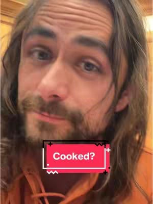 A close-up shot of a man with long hair and a beard. He is wearing an orange hoodie. A red and black box with the text Cooked? is overlaid on his face.