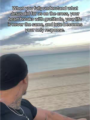 A man wearing a black durag stands facing away from the camera with a beach in the background. Text is overlaid in the top of the image.