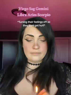 A woman with dark hair and makeup looks towards the camera with a serious expression. Text overlays list zodiac signs and a caption stating the signs are turning off their feelings. A small flame from a candle can be seen in front of the person.