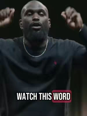 A man with a shaved head and a beard is the central figure, with his arms raised in a gesture of emphasis or excitement. The background is dark, putting the focus on the man who is wearing a black top. A text overlay at the bottom reads 'WATCH THIS WORD'.