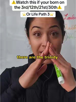 A woman with dark hair and fair skin is positioned in front of a light-colored background, likely a whiteboard. The top portion of the image contains overlaid text in a white box with a black border, and additional text, appearing to be a title or subtitle. In the center foreground, the woman is holding her hands in front of her face, pointing her thumbs towards each other. A green marker is visible, held by her right hand near the bottom. In the background, some handwritten words, including “Leader” and “Malik,” are partially visible, perhaps related to the content.