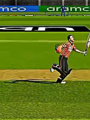 The image shows a digitally rendered scene of a cricket match. A cricketer, dressed in a colorful orange and black jersey and black trousers, is captured mid-run. He's holding a cricket bat and protecting his head with a helmet. He appears to be batting. The background features a green field and stadium infrastructure with the Aramco and MCO brand.