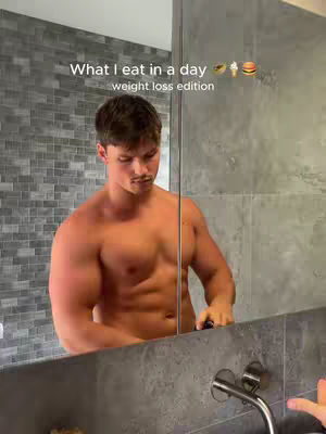 A shirtless man stands in front of a mirror in a shower. The cover image is a selfie showing the upper body of a man in a modern bathroom with gray-tiled walls. The man is muscular and appears to be taking a selfie with a smartphone, captured in the reflection of the mirror.