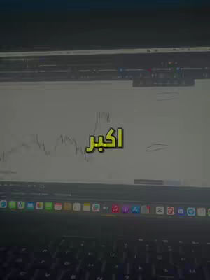 A laptop displaying a trading chart with a text overlay in Arabic. The laptop is open on a desk with the keyboard visible at the bottom. The overall color scheme is dominated by the dark tones of the laptop against the background, with the chart’s white lines providing contrast.