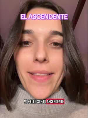 A woman with long brown hair is centered in the frame, looking directly at the camera. Overlay text at the top says "EL ASCENDENTE" in a purple box, and text at the bottom says "VOS ELEGISTE TU ASCENDENTE" in a red box. The background is a soft pink color.