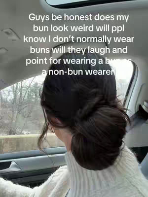 A woman in a car showing her hair bun, with a text overlay suggesting potential judgment about the hairstyle.