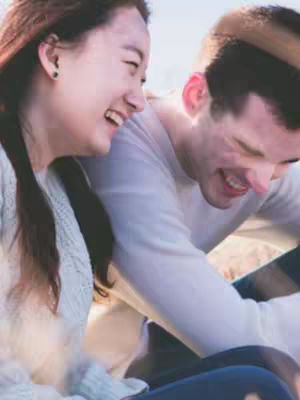 A cover image shows a woman and a man smiling and laughing, both gazing at each other. The woman is on the left, partially visible, with long, dark hair. The man is slightly to the right, his face closer to the camera and his expression joyful.