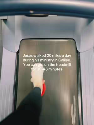 The image shows a first-person view of a treadmill. The treadmill belt has some text overlayed on it, and a person's arm and hand are visible, reaching for the red stop button.
