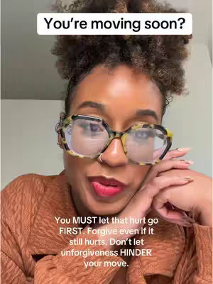 A close-up shot of a woman with curly hair and glasses, looking directly at the camera.
