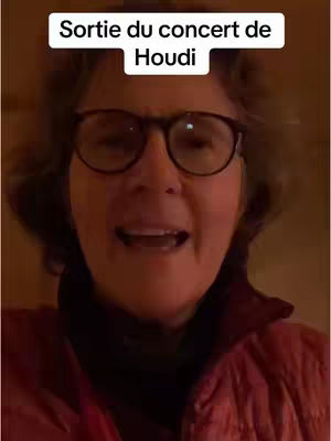 A selfie-style video cover featuring an older woman wearing glasses and a red jacket, with text overlayed at the top.