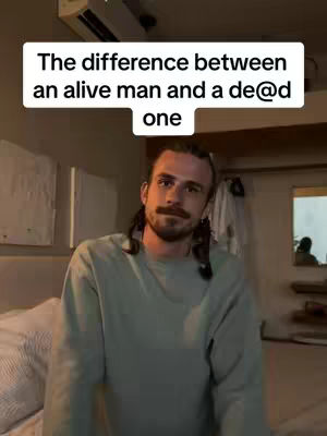 A man with a beard and long hair is centered in a room. Above his head is text in a white box.