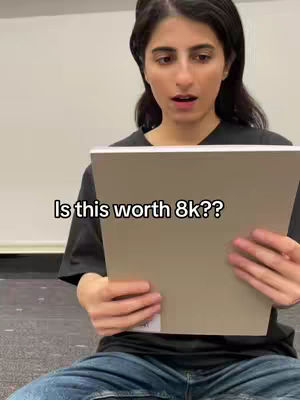 A young woman with dark hair sits with a notebook, looking surprised. Text overlayed on the image asks, "Is this worth 8k??".
