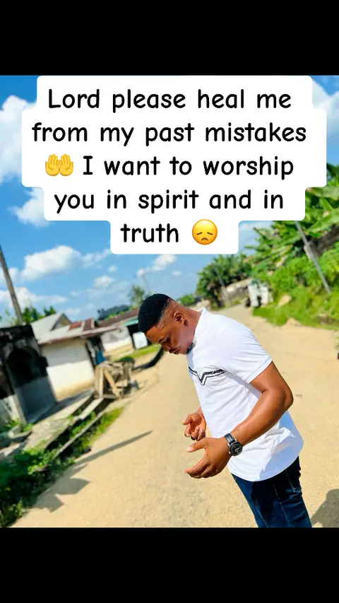 A man is standing outdoors on a sunny day. A white text box with black text is overlaid. The man is wearing a white t-shirt and dark pants, with a wristwatch and a thoughtful expression. A road and surrounding greenery form the background.