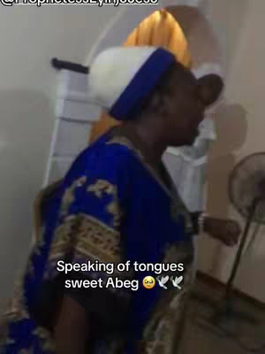 A woman in a blue and gold robe and a white and blue head covering is speaking. Text saying 'Speaking of tongues sweet Abeg' is overlaid.