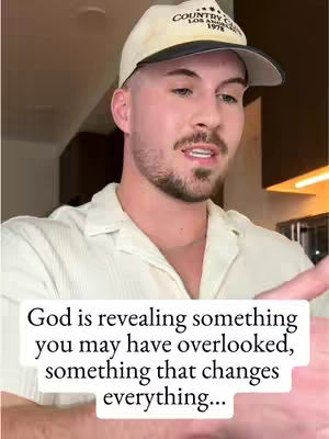 The image shows a man indoors, speaking directly to the camera. He's wearing a white shirt and a cream-colored baseball cap. The text overlay states: God is revealing something you may have overlooked, something that changes everything...