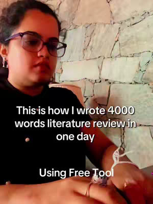 A woman wearing glasses looks down while sitting in front of a textured wall, with text overlayed on the image. The composition is typical of a selfie-style video with the subject in the foreground.