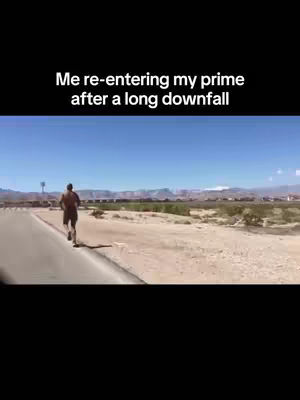 A man runs along a paved road in a desert-like environment under a bright blue sky. Text overlay at the top reads, 'Me re-entering my prime after a long downfall'.