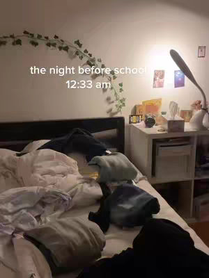 A messy bed is the primary focus, with rumpled sheets and scattered clothing. A nightstand with various items, including a lamp illuminating the scene, is visible in the background. The text overlay indicates the time: 12:33 am.