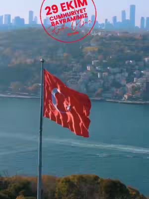 The cover image shows the Turkish flag waving on a flag pole near a body of water. In the background are buildings that form a cityscape, and the overall scene is captured against a soft-focus, hazy background. A circular text overlay with red font is added at the top that includes text related to the 29th of October.
