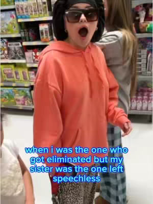The cover image shows a young woman indoors, likely in a store, reacting with wide-eyed surprise and her mouth open. She wears sunglasses, a head covering, and a light orange hoodie. Text at the bottom describes the situation as a surprise about elimination in a game.