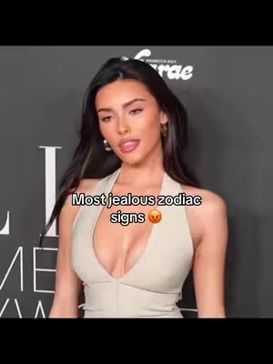 A woman with long, dark hair and fair skin is the central focus. She is wearing a cream-colored halter top. Text over the image reads 'Most jealous zodiac signs' and has an angry face emoji.