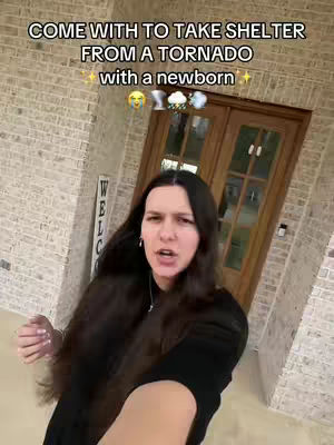 A woman with long dark hair stands in front of a brick-covered exterior wall and a wooden door. The video has text overlays with emojis.