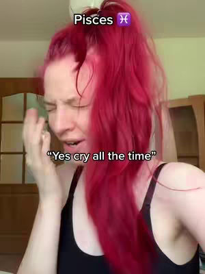A woman with bright red hair is shown from the chest up, looking distressed. Text overlays the image. The background is muted, with a glimpse of a room and a wooden cabinet.
