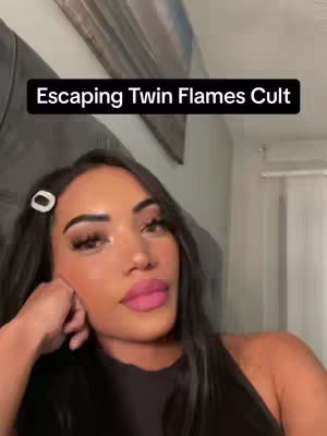A woman with long dark hair and a white hair clip poses while supporting her head, pink lipstick is visible, with a black rectangle at the top declaring Escaping Twin Flames Cult.