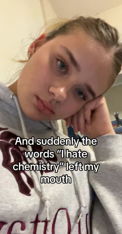 A selfie-style image with a young woman tilting her head and resting her cheek on her hand. The background is slightly blurred. Text is overlaid on the image.