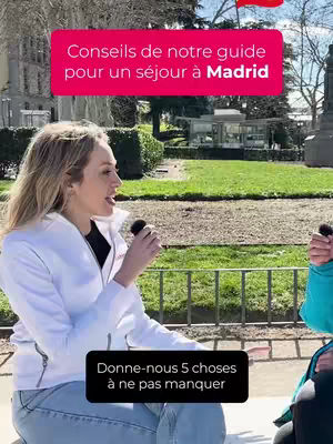 The cover image shows a woman in a white jacket speaking into a microphone in an outdoor setting. Two text boxes overlay the image with phrases, one pink and one black. The background consists of greenery and buildings.