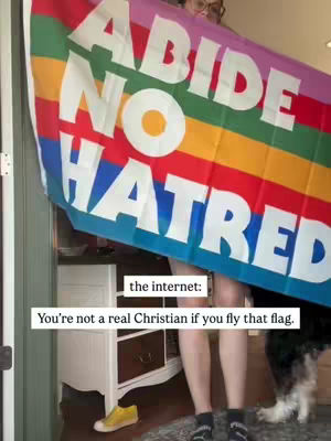 A person holding up a rainbow flag with text that reads 'ABIDE NO HATRED' . The person is partially visible, standing. There's text at the bottom reading 'the internet:' and 'You're not a real Christian if you fly that flag.'
