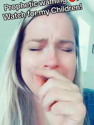 A close-up shot of a woman's face with closed eyes. She is biting her lower lip, her hand covering her mouth. The background shows a light green wall.