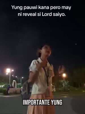 A woman is walking towards the camera at nighttime, with streetlights illuminating the area. She is wearing a white shirt and a light-colored skirt, with a backpack slung over her shoulder. Text overlays are added at the top and bottom of the image on separate lines.