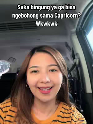 A woman with long brown hair is smiling and looking at the camera. She is wearing a striped yellow and black shirt. Above her, there is text. The background shows a car interior
