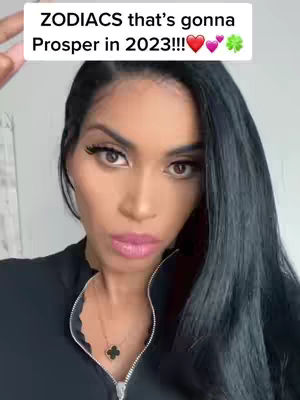 A woman with long, dark hair and a black top is looking towards the camera. Overlayed above her head is text reading: "ZODIACs that's gonna Prosper in 2023!!!" with heart and clover emojis.