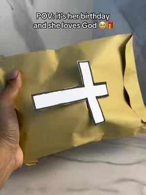 A hand is holding a wrapped gift with a white cross design on top. Text is overlaid at the top of the frame.