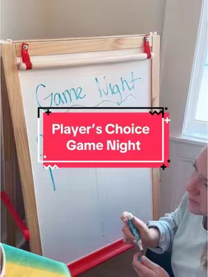 A person is shown partially, holding a pen in front of a whiteboard with the words "Game Night", a red and white sign that says, "Player's Choice Game Night".