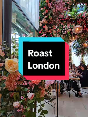 The cover image displays a restaurant setting with an abundance of floral decor. A large black, turquoise, and red text box in the center reads 'roast London' in white text. The background shows tables with people dining, lush floral arrangements, and hanging globe-like lights.