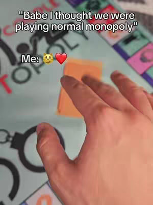 A hand rests on a Monopoly game board featuring the word "Monopoly" and other game-related elements. Text overlays appear at the top and bottom of the image.