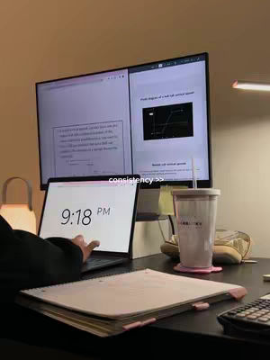 A desk setup with a large monitor and laptop displaying study materials. A notebook and a drink are on the desk. The time 9:18 PM is visible on the laptop screen.
