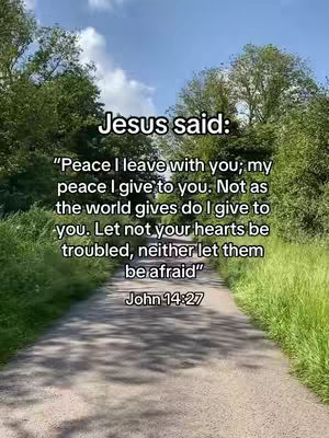 An image depicts a pathway through a natural setting with text overlaying the scene. In the background, the sky is visible, partially obscured by the tops of tall, green trees. On either side, tall green grass and trees line the path, creating a tunnel effect. The text overlay begins with 'Jesus said:' and quotes a passage from John 14:27.