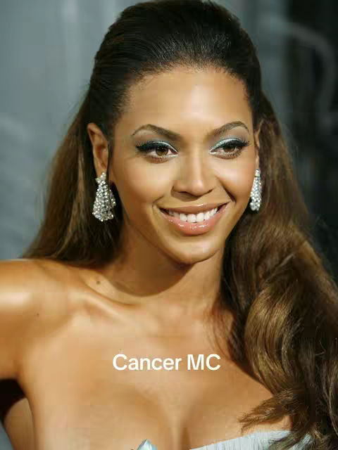 The cover image features a close-up of Beyonce, with her face and upper chest visible. She is smiling with a slight tilt of the head, revealing a bright smile suggesting her positive mood. She wears sparkling earrings. The image has a professional look, likely a promotional shot or a still from a video. Text overlayed on the image reads Cancer MC.
