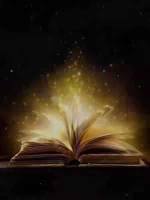 An open book with golden light radiating from its pages against a dark background. Stardust-like particles are scattered around the light and throughout the dark space.