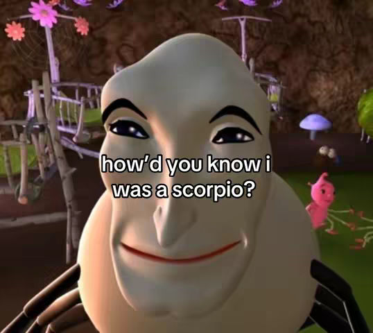 A still from a cartoon featuring a character with a large, light-colored head and a smiling expression. The character has dark eyes and eyebrows and is set against a whimsical background with cartoon plants and structures. Text is overlaid on the image.