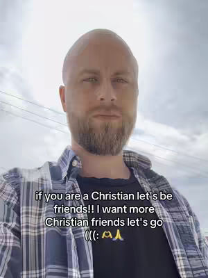 A man with a shaved head and a beard stands outdoors, facing the camera. He wears a plaid shirt over a black T-shirt. Text overlays on the image suggest a call for Christian friends.