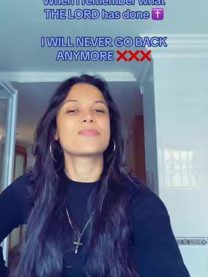 A woman with long, dark hair wearing a black top stands in front of a partially visible white door. Above her, overlaid text reads, 'When I remember what THE LORD has done' followed by 'I WILL NEVER GO BACK ANYMORE', with a cross and 'XXX' emojis respectively. The lighting is soft, and the overall composition suggests a moment of personal reflection.