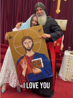 A woman and two men are holding up a painted icon of Jesus, appearing to be in a church setting, with one man hugging the woman.