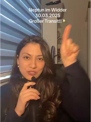 A woman with long, dark hair is holding a microphone and gesturing with her right hand. Text overlays on the image indicate astrological information, including the planet Neptune.