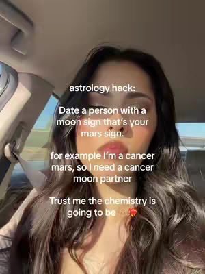 A woman in a car, looking towards the camera. Text overlays on the image provide an astrology tip: dating someone with a moon sign that matches your Mars sign.