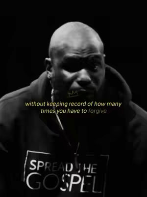 A black and white image featuring a man in a black hoodie against a dark background. Overlayed text in a pale yellow shade reads, "without keeping record of how many times you have to forgive". The man has a shaved head and a focused expression, with a small crown graphic near his left eyebrow. A portion of a t-shirt with the words "SPREAD THE GOSPEL" is visible. The image is sharply lit, highlighting the subject and overlay text.